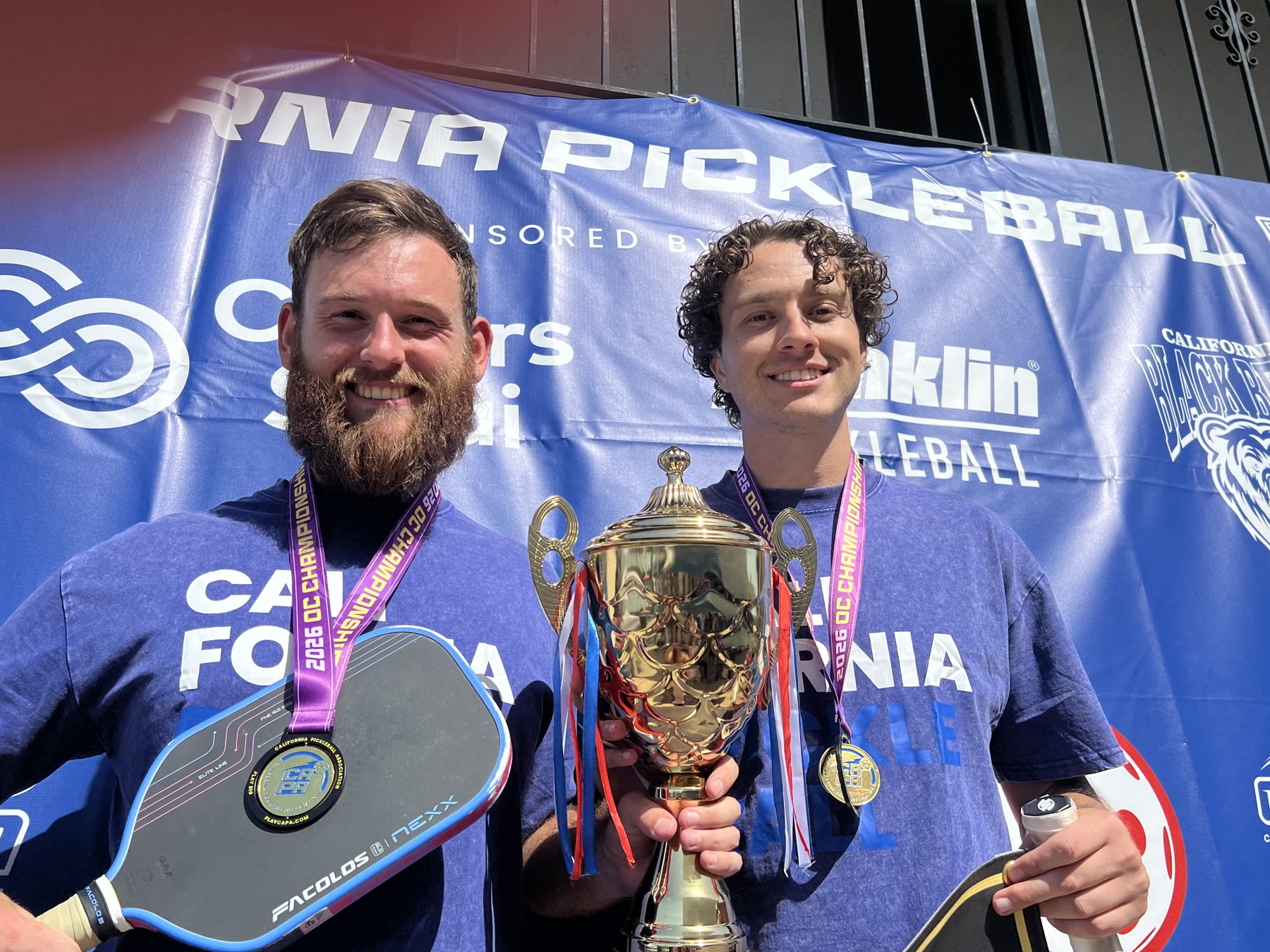 Oliver Lynch and his partner holding their CAPA gold trophy and medals